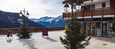 Un refugio de montaña con fachada de madera, un letrero y vistas a montañas nevadas.