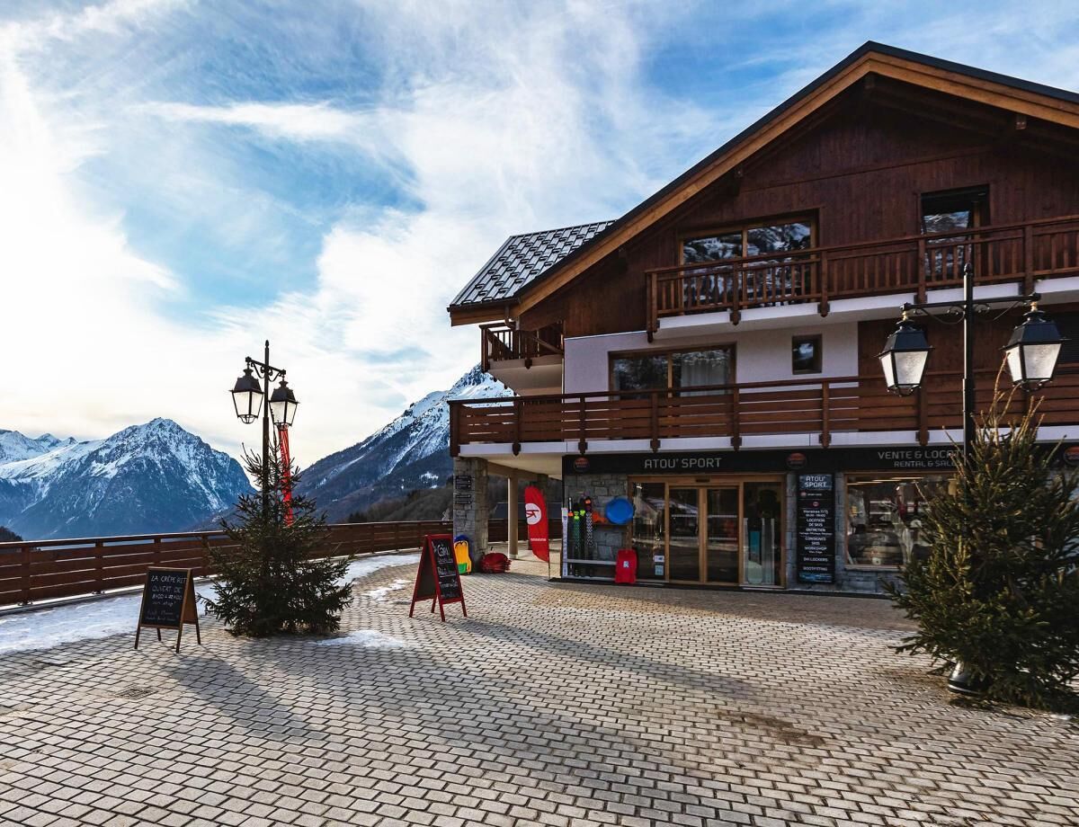 Ein Holzhaus mit Balkon, einem Schild und Blick auf die Berge.
