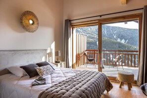 A bedroom with a large bed, a balcony with chairs, and a view of mountains. - Wifi, 25m from ski slopes, balcony, parking, tv, ski locker, 77m², Vaujany (Vaujany)