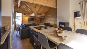 Una cocina moderna y acogedora con techo de madera, una isla central y un comedor con mesa y sillas.