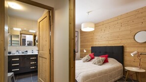 Un dormitorio con cama, almohadas, mesita de noche y lámpara.