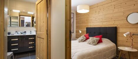 Ein Schlafzimmer mit Bett, Kissen, Nachttisch und Lampe.