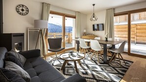 Una sala de estar moderna con sofá, mesa de comedor, sillas y chimenea.
