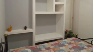 Een kamer met een bed, een wit inbouwkasten en een kleine potplant.