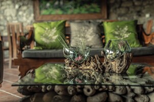 Una mesa de centro de vidrio con un centro de mesa rústico y dos jarrones de vidrio con plantas.