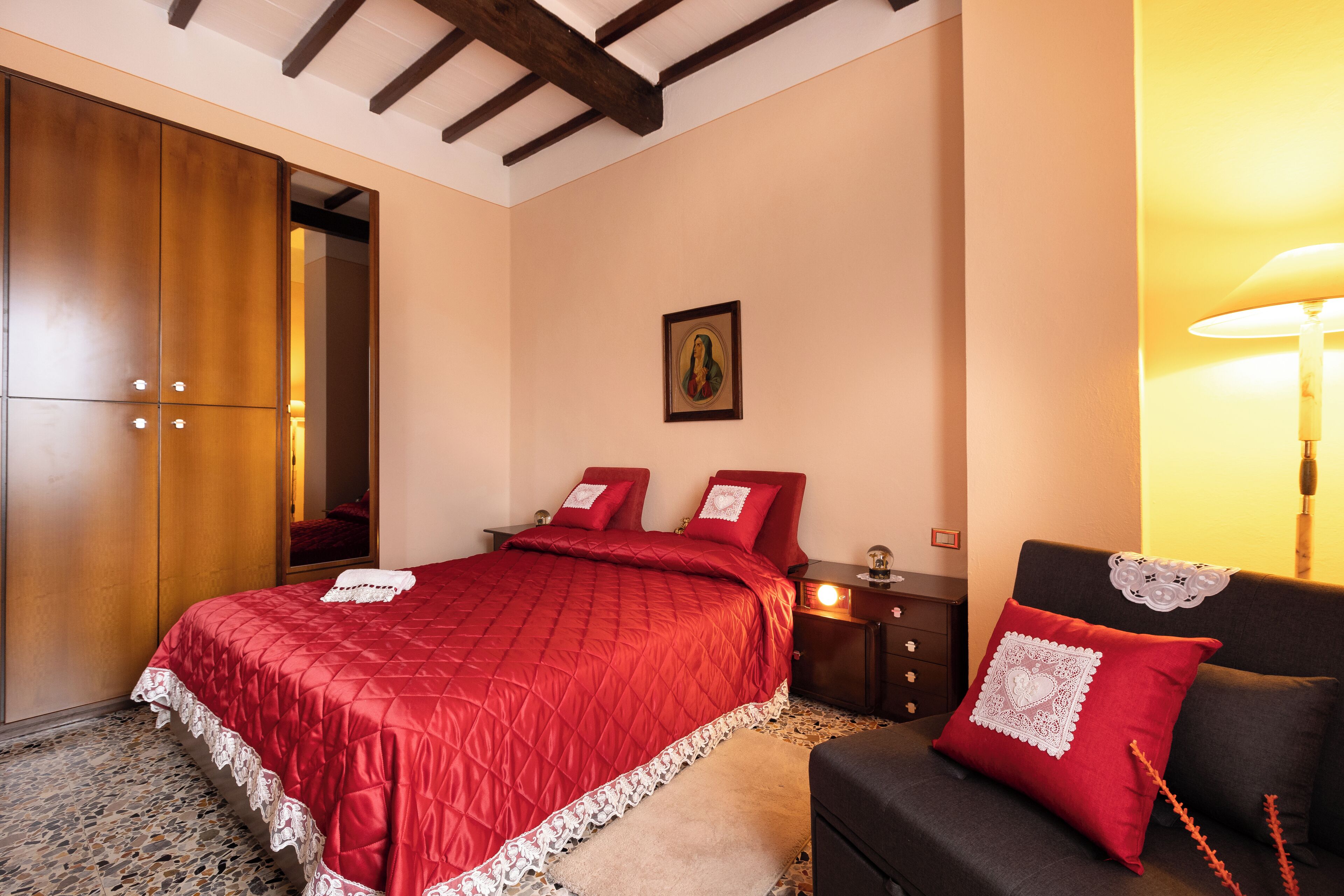 A bedroom with a large bed, a nightstand, a dresser, and a wall-mounted lamp.
