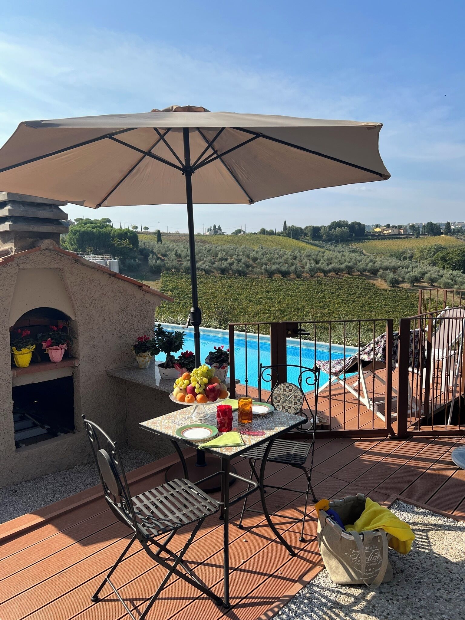 An outdoor patio with a table set for two, a pool, and a view of the countryside.