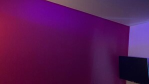 Eine Decke mit blauer LED-Beleuchtung und einem an der Wand montierten Flachbildfernseher.