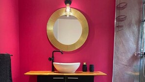 Ein Badezimmer mit einem schwarzen Waschtisch, einer weißen Spüle und einem goldfarbenen Spiegel.