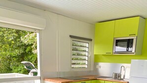 Eine kleine Küche mit Essbereich, einem Kühlschrank, einer Mikrowelle und einem Fenster mit Jalousien.