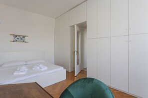 Un dormitorio con una cama, un sillón verde y armarios blancos.
