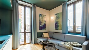 Un salon moderne avec un canapé gris, deux tables basses rondes et des œuvres d’art abstraites accrochées au mur.