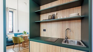Une cuisine compacte dotée de meubles en bois, d’un évier en acier inoxydable et d’un coin repas avec un canapé bleu et une chaise verte.