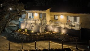Un edificio con un muro de piedra, una escalera y un balcón con barandillas.