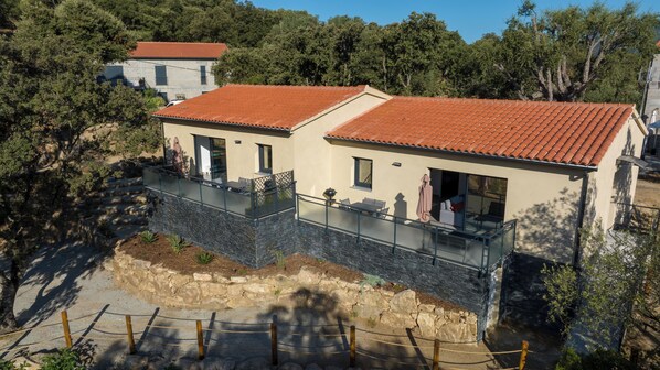 A two-story building with a red-tiled roof, a balcony, and a stone foundation. - Casa Emma (Sollacaro)