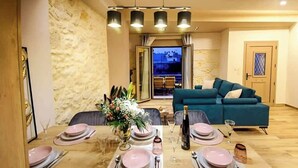 A dining area with a table set for four, a sofa, and a view of the outside.