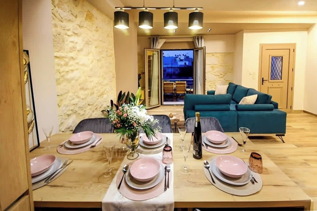 A dining area with a table set for four, a sofa, and a view of the outside.