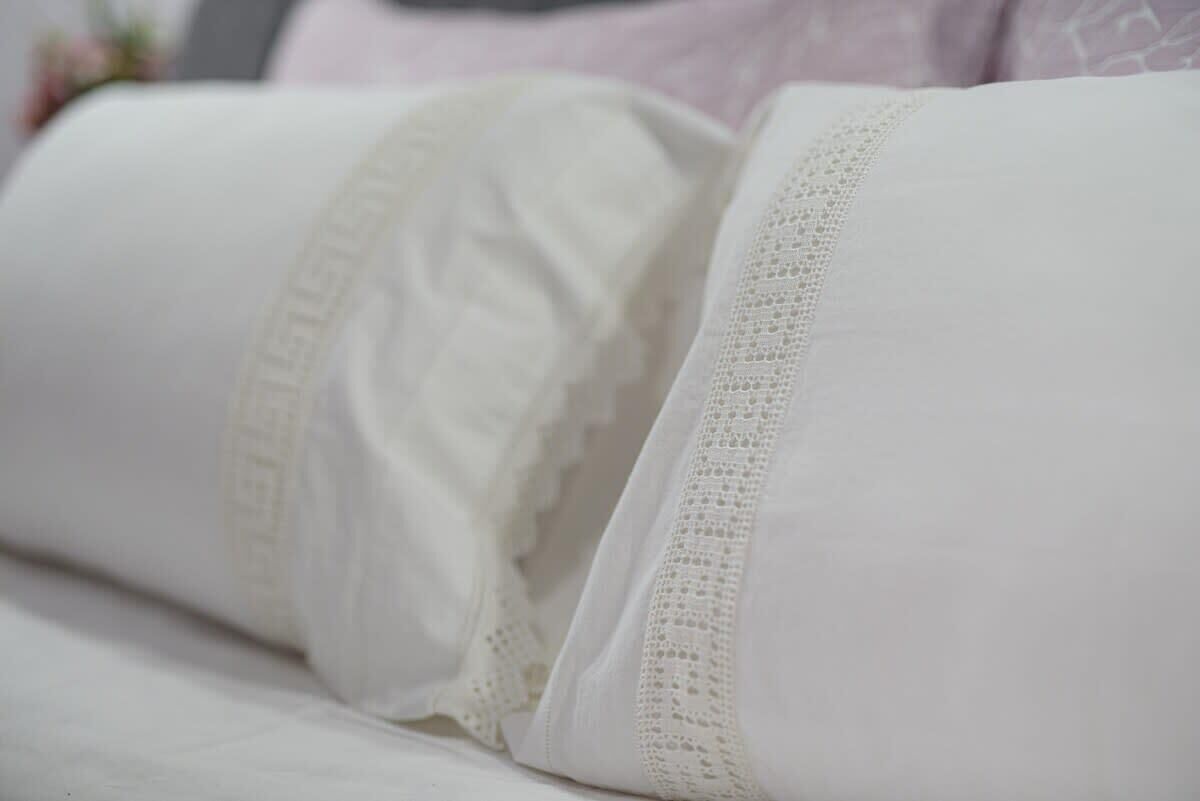 A bed with white bedding and lace trim.