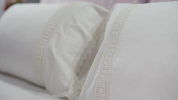 A bed with white bedding and lace trim.