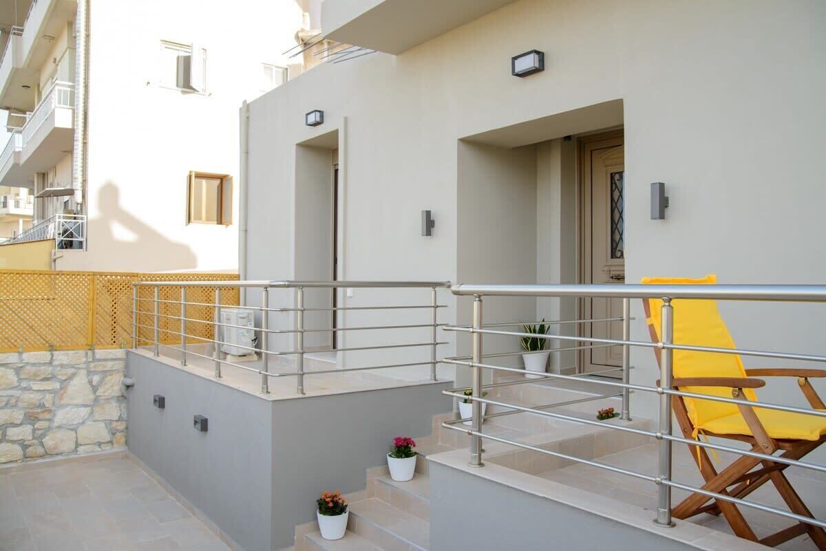A balcony with a metal railing, a yellow chair, and potted plants.
