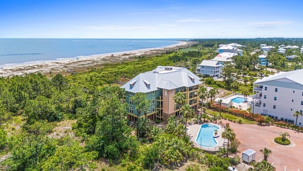 Een resort met meerdere gebouwen, een zwembad en uitzicht op het strand.