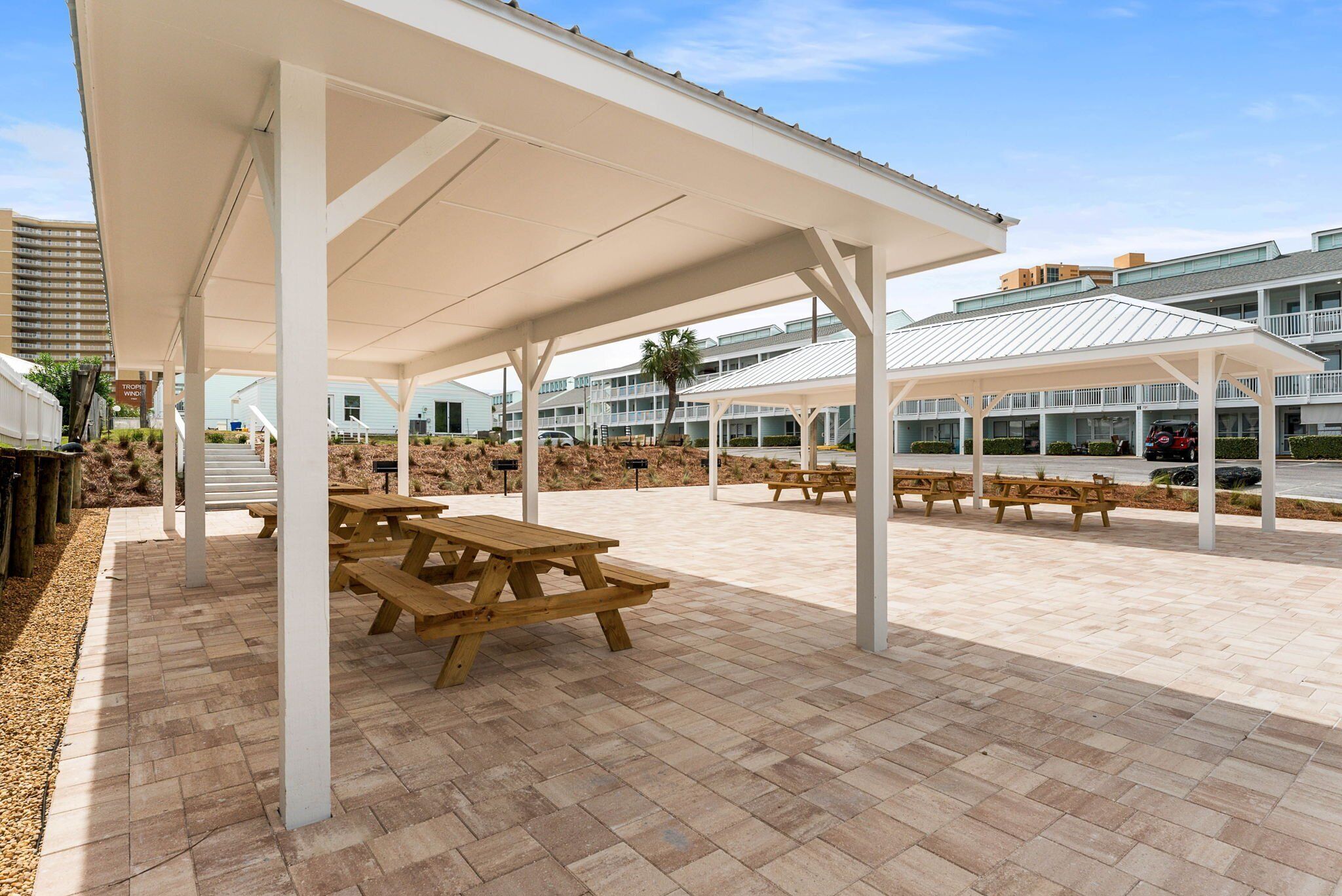 Un patio al aire libre con mesas de picnic y zonas de estar cubiertas.