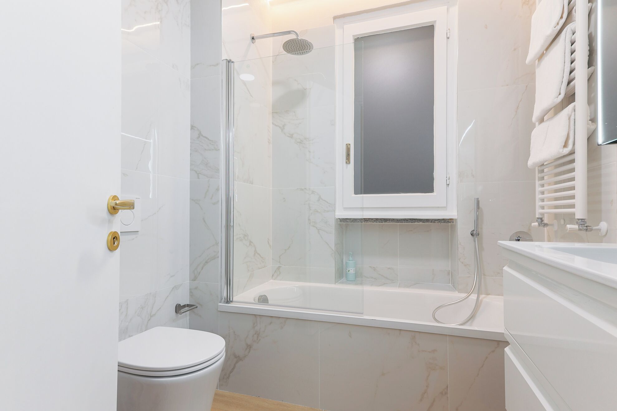 A modern bathroom with a glass-enclosed shower, a toilet, and a bathtub.