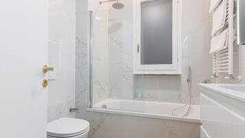 A modern bathroom with a glass-enclosed shower, a toilet, and a bathtub.