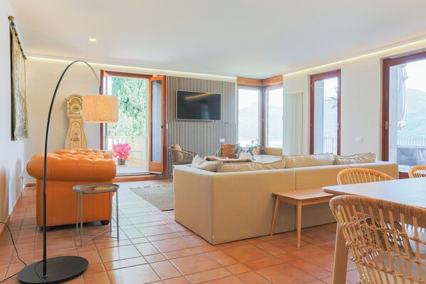 A modern living room with a sofa, a dining table, and a television.