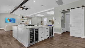 Una cocina amplia con una isla central, armarios blancos y un ventilador de techo.