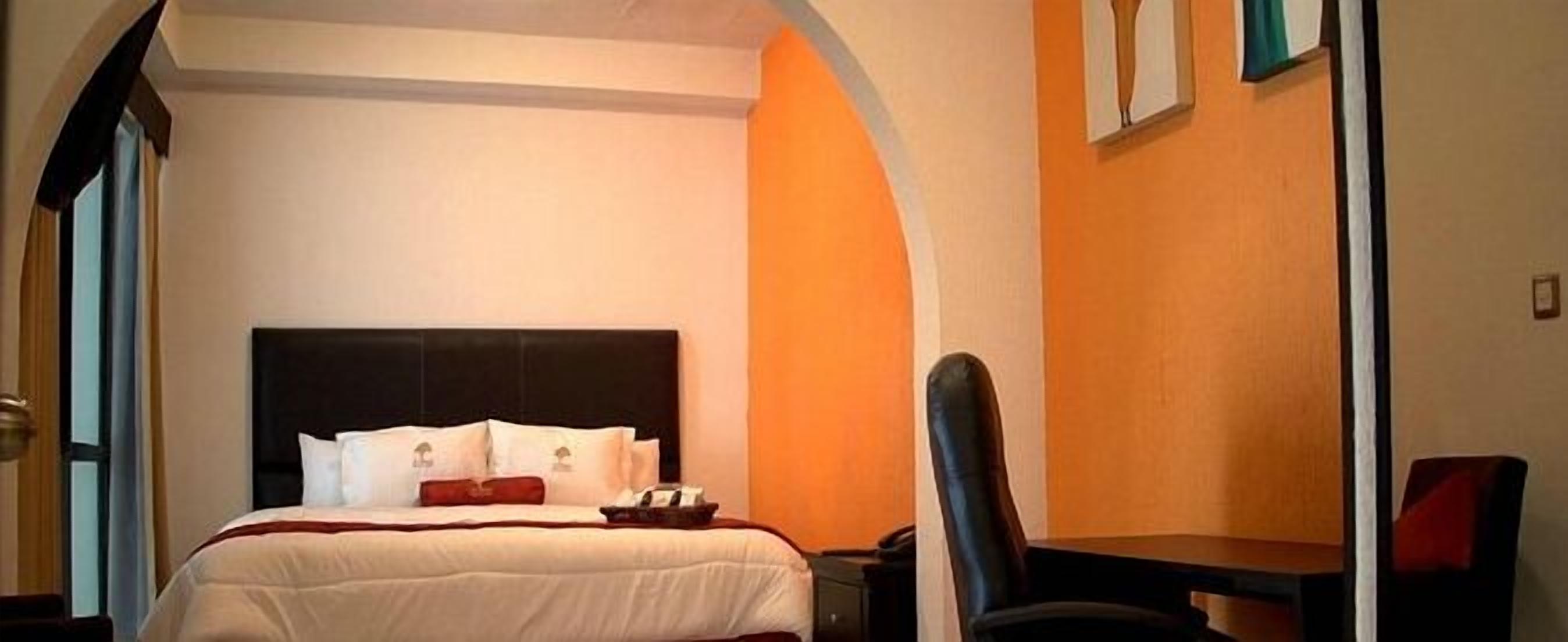 A hotel room with a bed, a desk, and a chair.