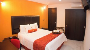Una camera d'albergo con un letto, una scrivania, una sedia, una televisione e un armadio.