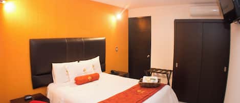 Una habitación de hotel con cama, escritorio, silla, televisor y armario.