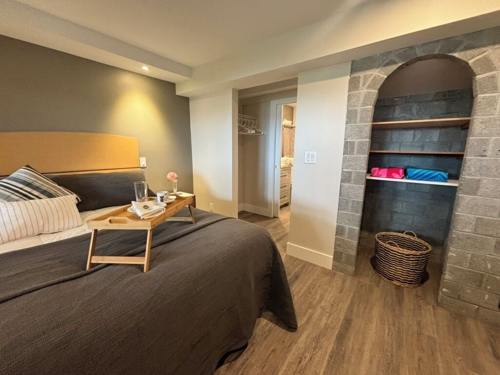 A bedroom with a bed, bedside table, and a stone fireplace.