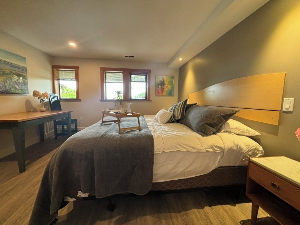 A bedroom with a bed, bedside table, and a desk.