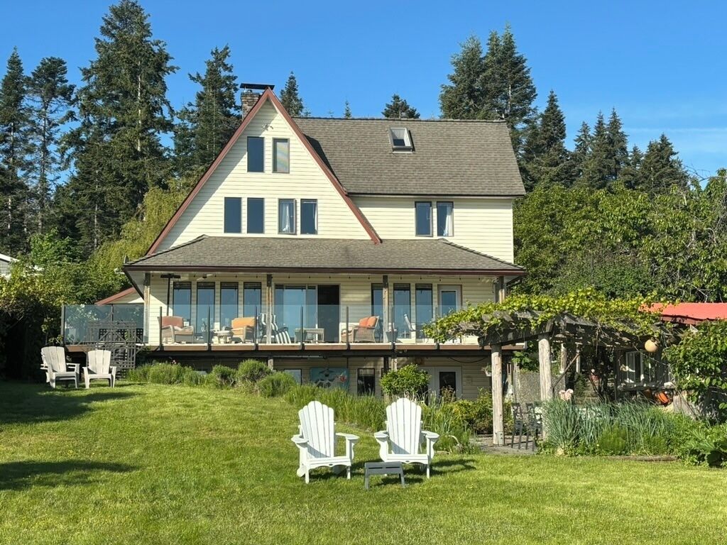 A two-story house with a large deck and a covered outdoor area.