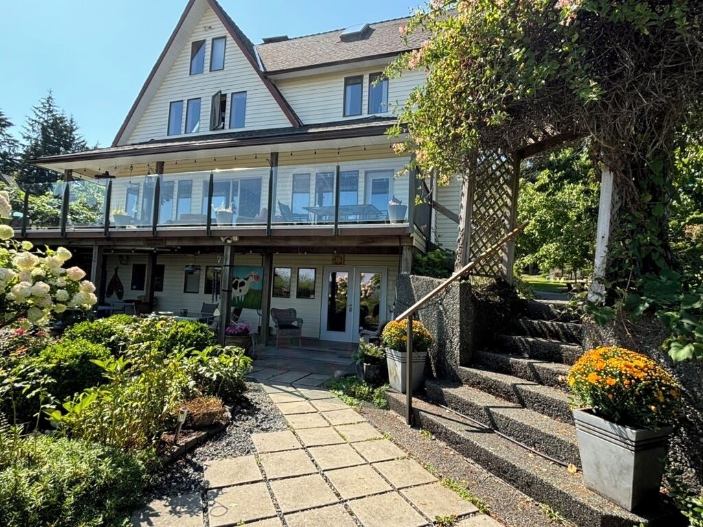 A two-story house with a covered porch, a staircase, and a garden with various plants and flowers.