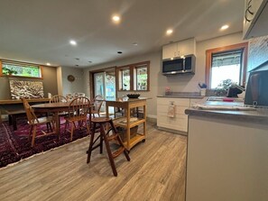 Une cuisine moderne avec un plancher en bois, un coin repas avec des chaises, un four à micro-ondes et des placards.