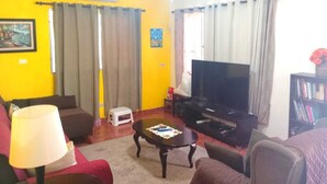 A living room with a TV, sofa, and a small table. - Spacious and relaxing beach house in Paradise to share with family or friends (El Higo)