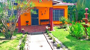 A house with a red roof, orange walls, and a small garden with plants and a pathway. - Spacious and relaxing beach house in Paradise to share with family or friends (El Higo)