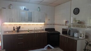 A kitchen with dark wooden cabinets, a granite countertop, a stove, a microwave, and a coffee maker. - Spacious and relaxing beach house in Paradise to share with family or friends (El Higo)