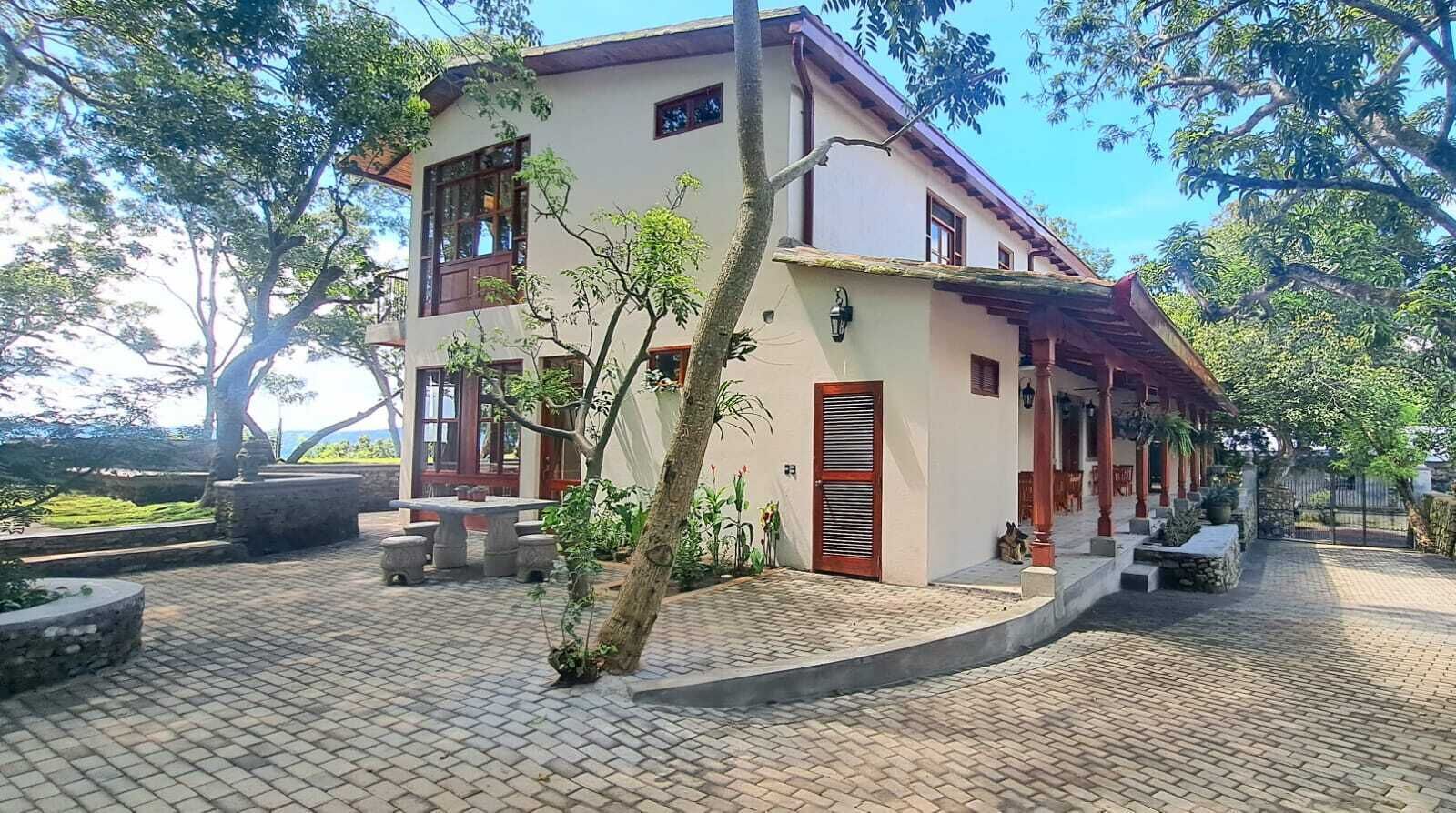 Un bâtiment à deux étages doté d’une terrasse carrelée, d’un espace extérieur aménagé pour s’asseoir et d’un petit jardin.