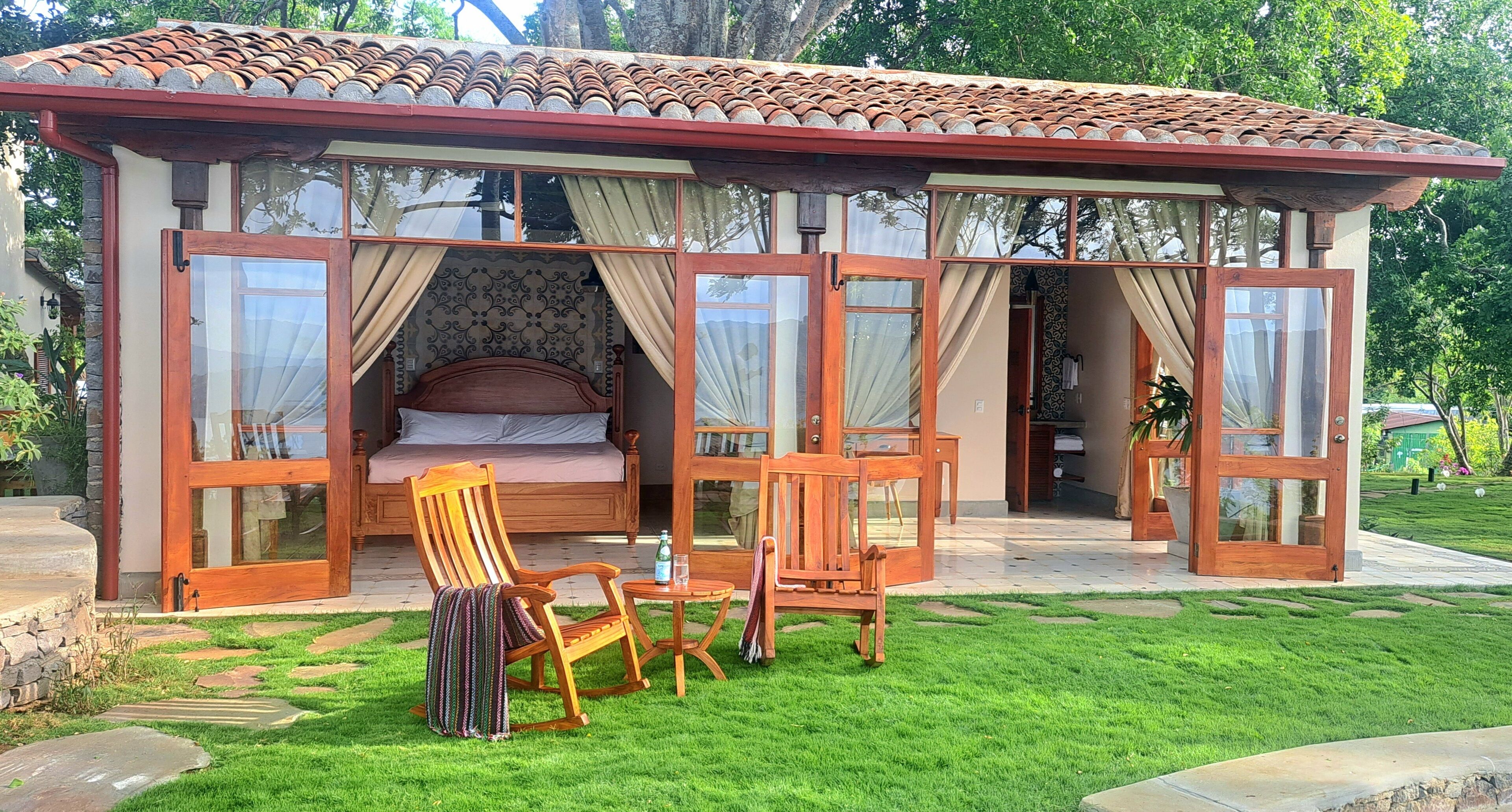 Un dormitorio acogedor y de planta abierta con una cama grande, muebles de madera y un ventanal que da al baño.