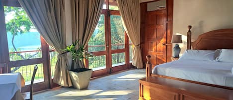 Un dormitorio con una cama de madera, una planta en maceta, una mesa y vistas al exterior.