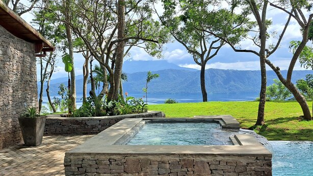 Un edificio de piedra con piscina de piedra y vistas a un lago y montañas.