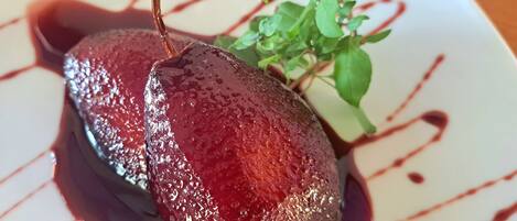 A pear with a glossy glaze and a sprig of greenery on a plate.