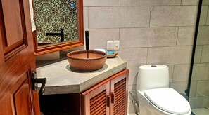 A bathroom with a wooden vanity, a ceramic basin, a toilet, and a patterned wall. - El Guayacán (Masaya)