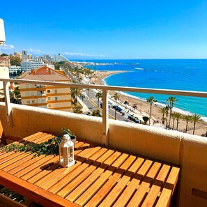 A balcony with a wooden table, a potted plant, and a lantern.