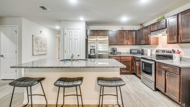 A modern kitchen with granite countertops, stainless steel appliances, and wooden cabinets. - Palm Coast Duplex w/ Screened Patio, Near Beaches! (Palm Coast)