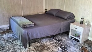 Una cama individual con una manta, una mesita de noche con una lámpara y una revista.
